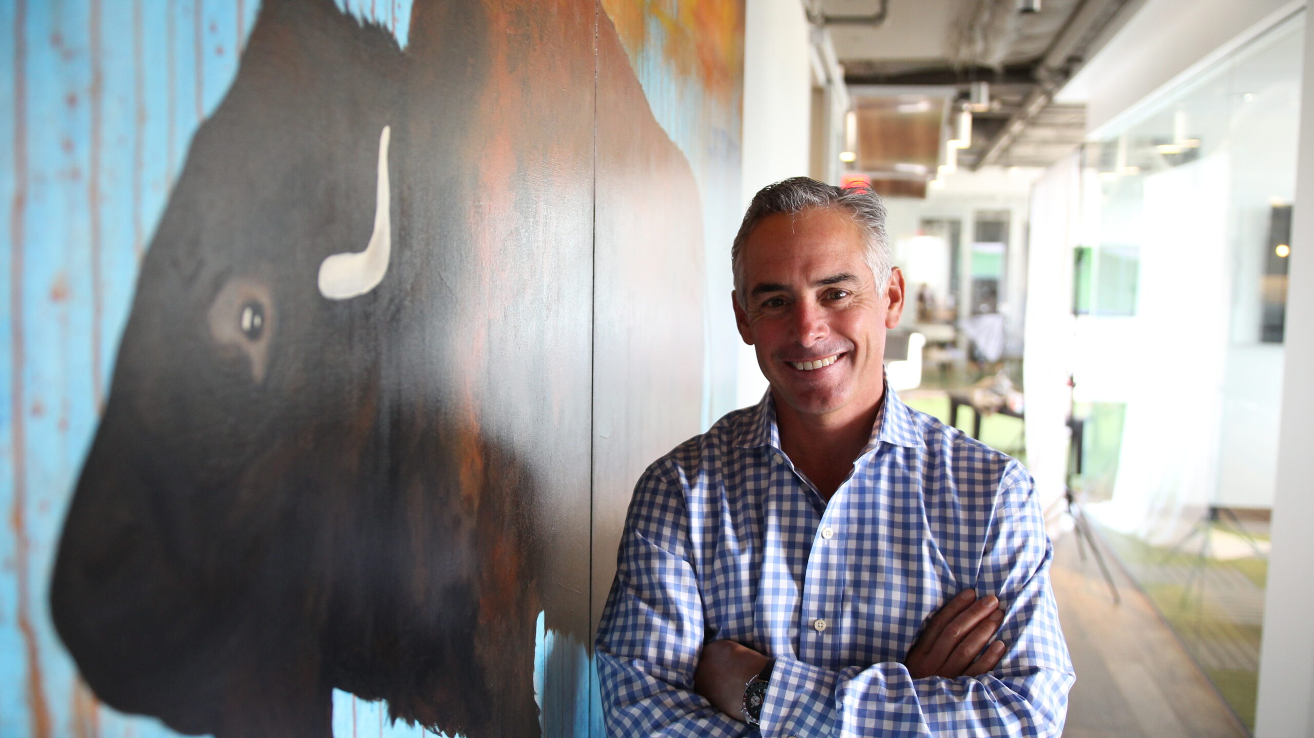 Kyle Ragsdale, posing in front of wall art featuring a buffalo